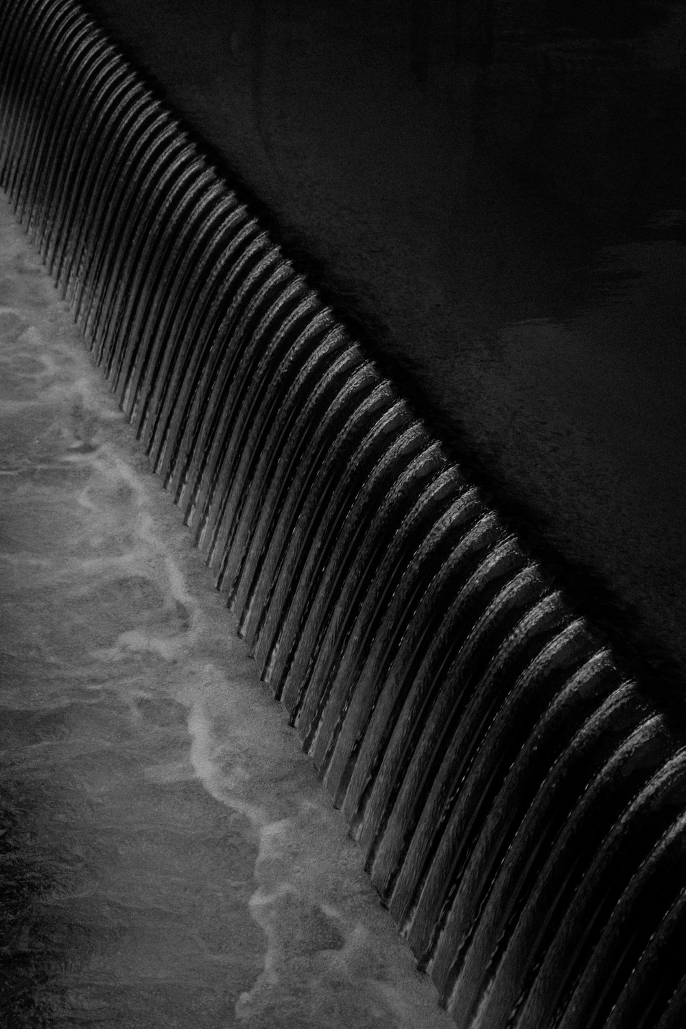 a black and white photo of water flowing over a wall