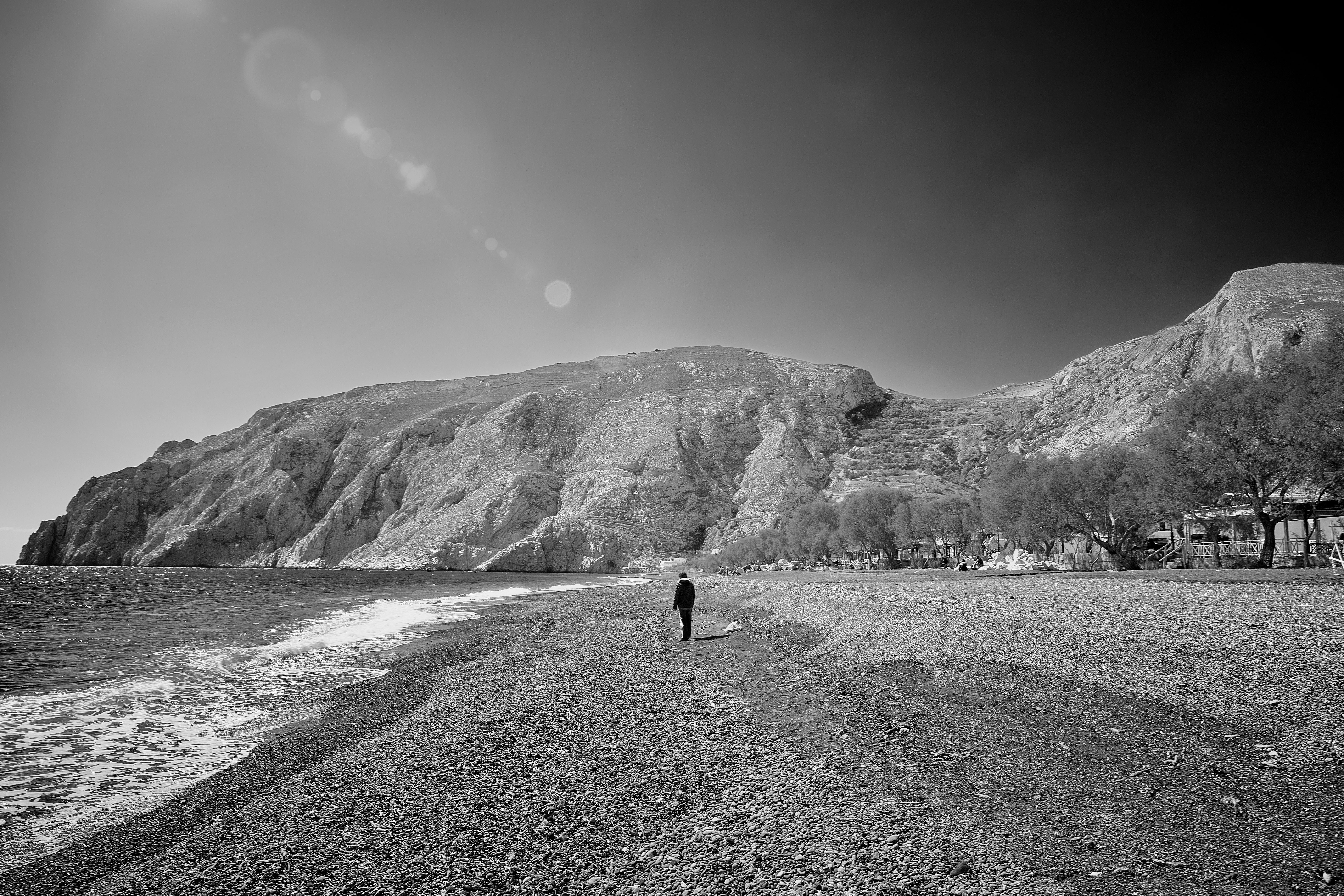 greyscale photo of person walking on seashore