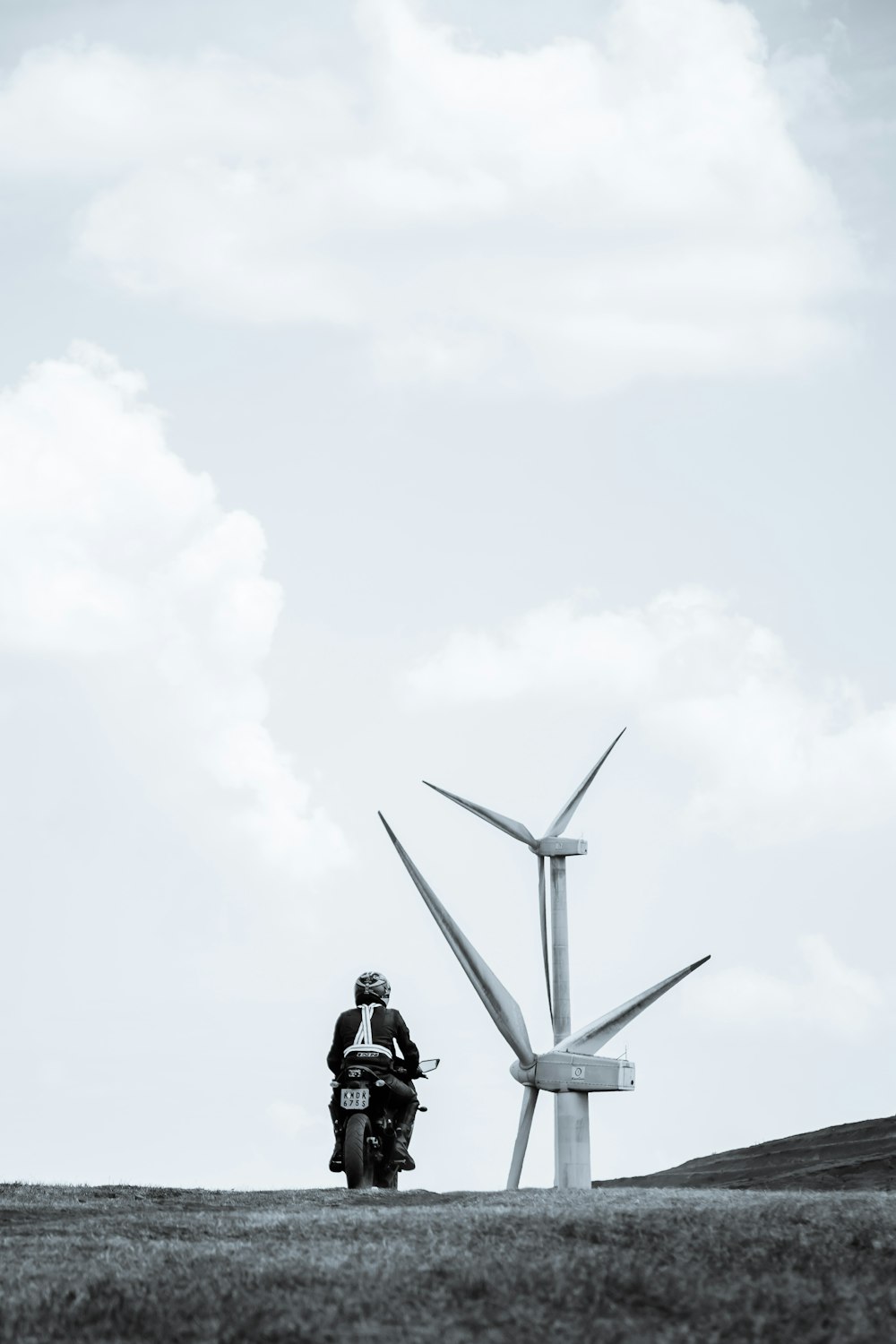 a man riding a motorcycle next to a wind turbine
