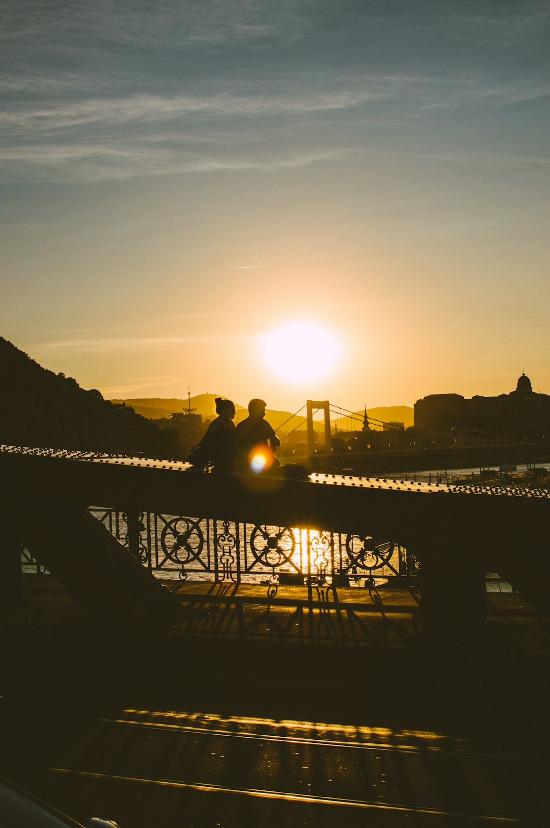 silhouette of two people at a bridge