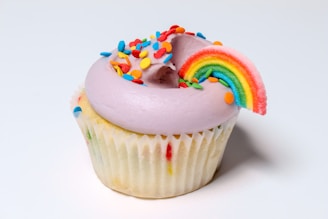 A pastel-colored cupcake with dairy-free frosting and a sprinkle of edible flowers.