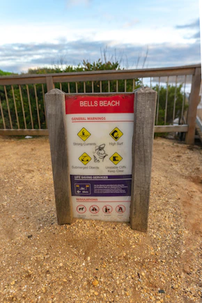 A series of beach safety icons displayed within an Indigenous art-inspired frame, showing warnings in multiple languages.