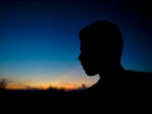 A silhouette of a figure framed by fading indigo light, blending into near-black.