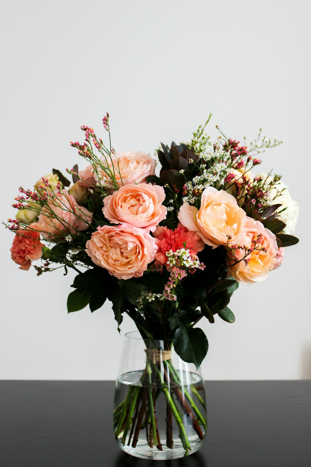 pink, beige, and red flower bouquet in clear glass vase