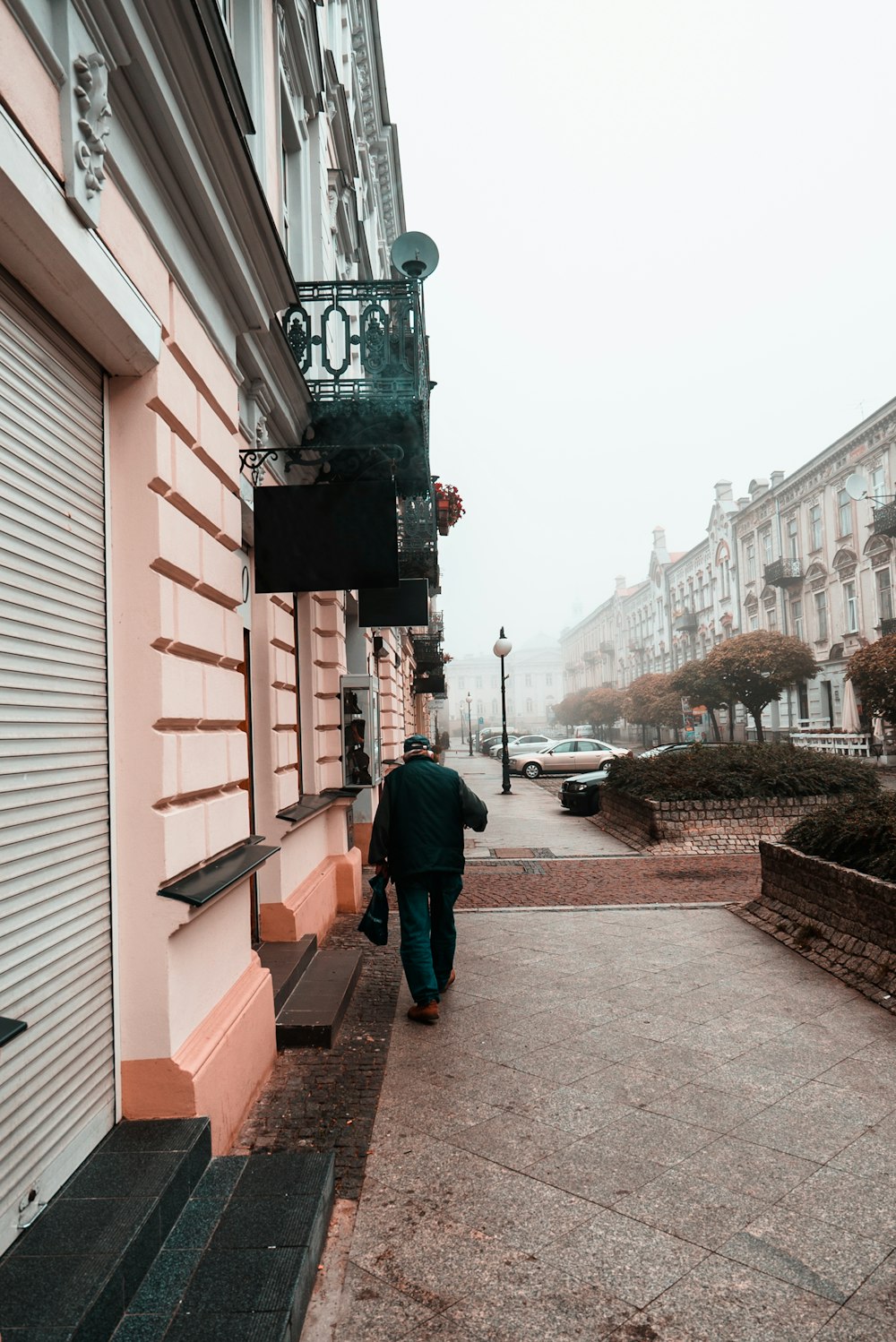 흰색과 갈색 건물 앞 보도를 걷고 있는 남자