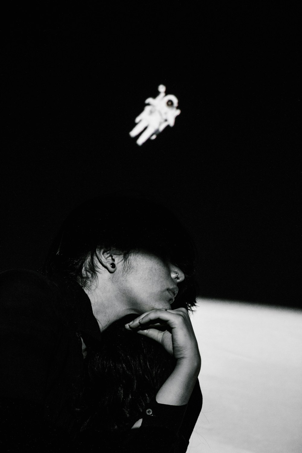 uma foto em preto e branco de uma pessoa sentada no escuro