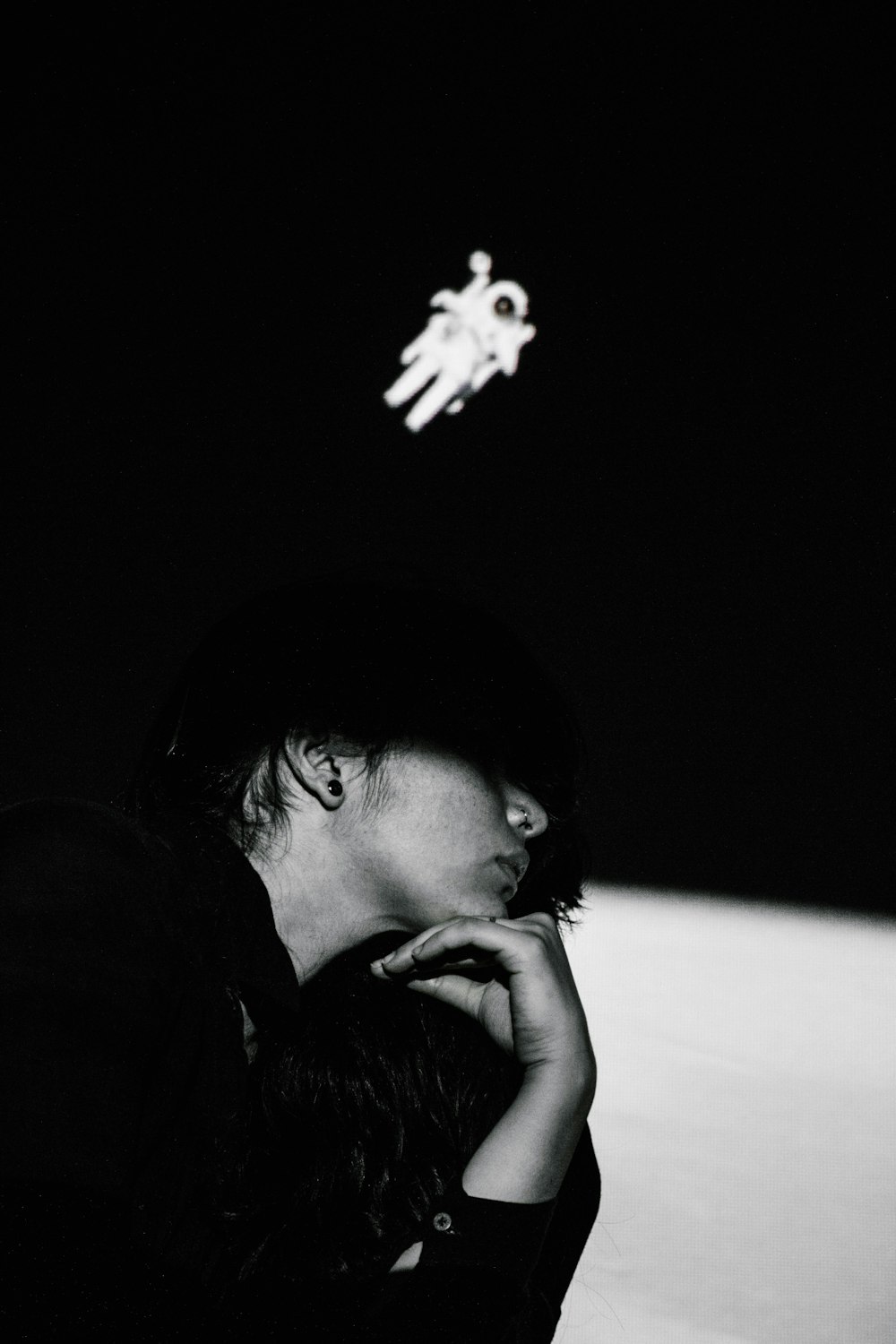 a black and white photo of a person sitting in the dark