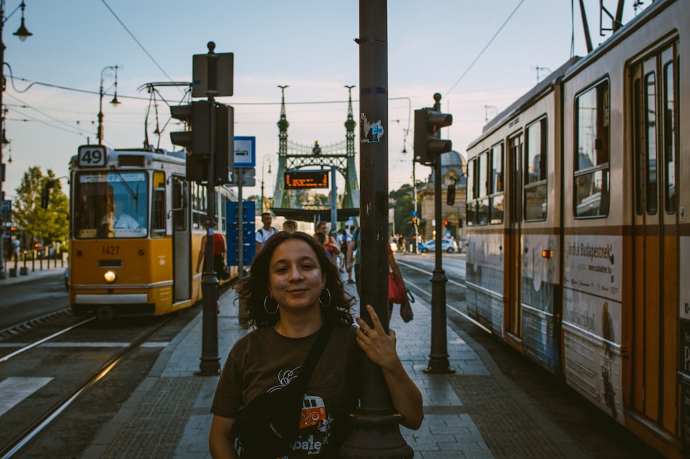 黄色い路面電車の横の黒いポールにつかまって立っている女性