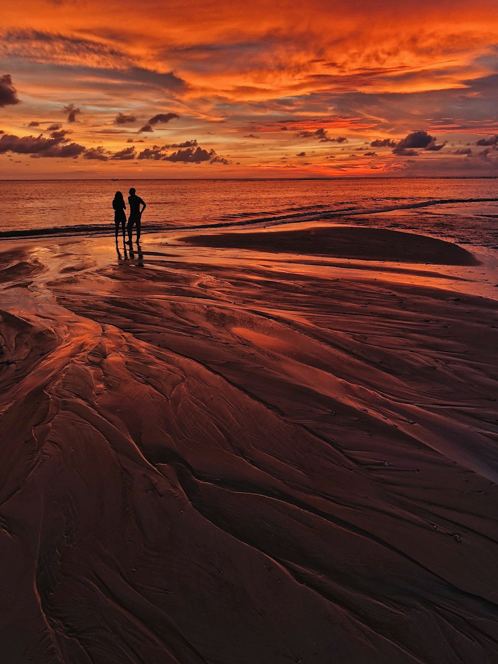 silhouette of man and woman standing on seashore