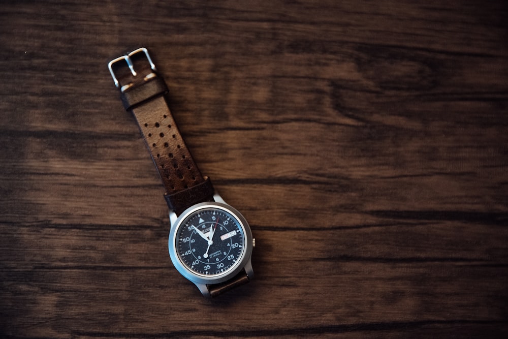 round silver-colored analog watch with brown leather strap