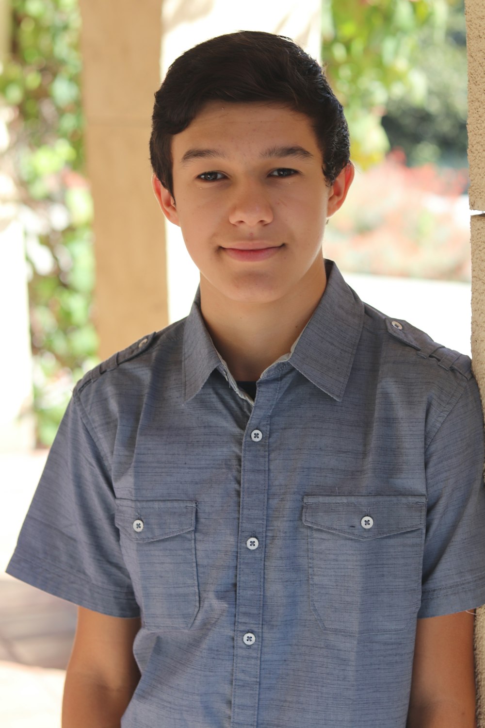 man wearing blue polo shirt standing near brown post