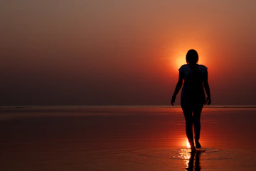 silhouette of woman walking on seashore