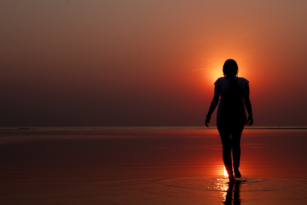 silhouette of woman walking on seashore