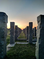Stone-like illuminated pillars lining a serene garden pathway at dusk.
