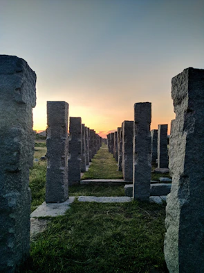 Stone-like illuminated pillars lining a serene garden pathway at dusk.