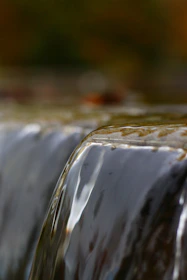 Close-up of water gently spilling over a custom-designed tiered waterfall at sunset.
