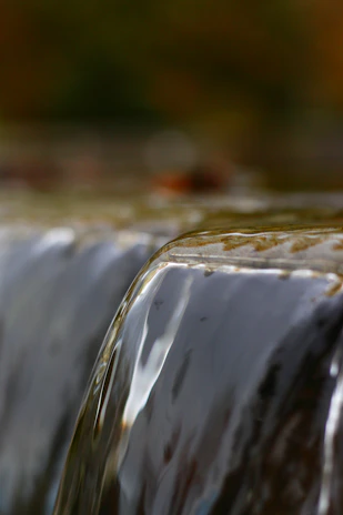 Close-up of a detailed artisan waterfall with smooth water flow and earthy tones.