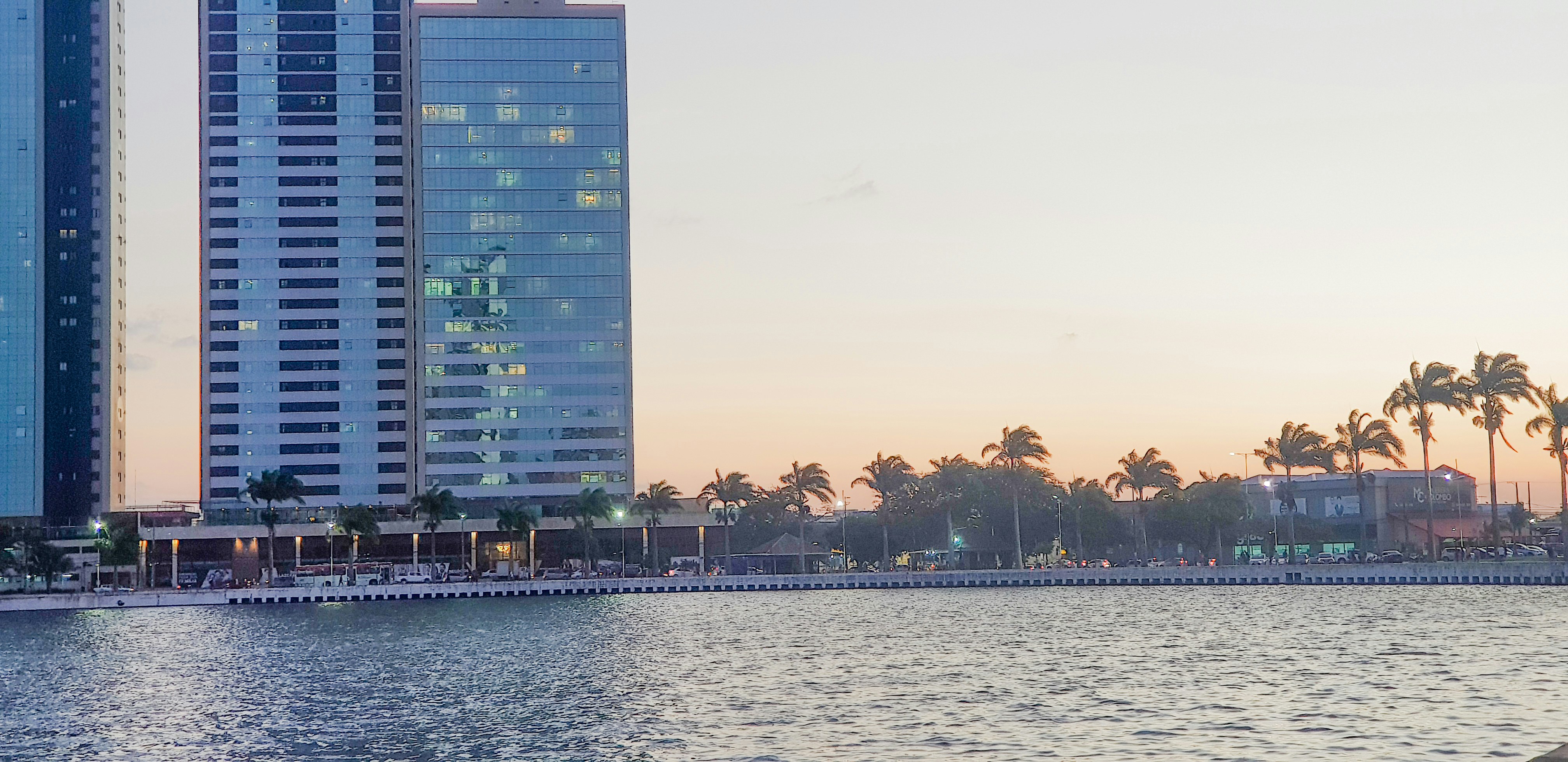 Modern glass residential towers rising above the Dubai coastline at sunset