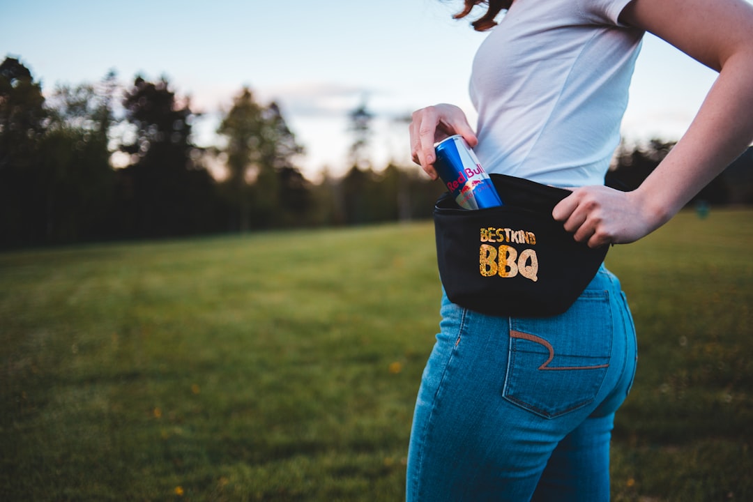 woman standing while putting Red Bull energy drink can on her fanny pack