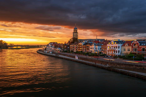 city with high-rise buildings near body of water under orange sky during night time