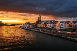 city with high-rise buildings near body of water under orange sky during night time