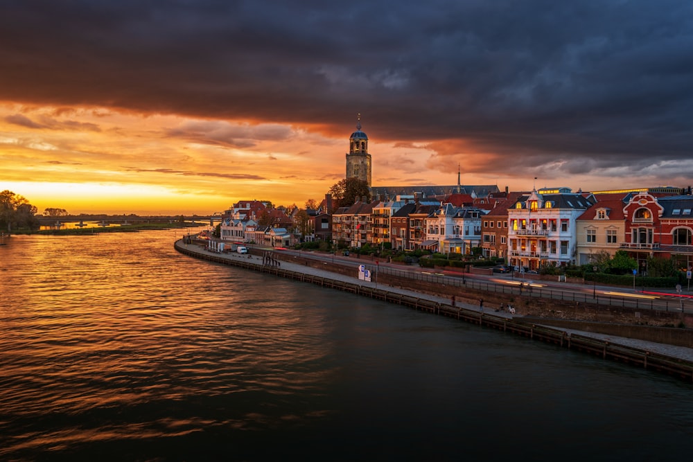 city with high-rise buildings near body of water under orange sky during night time