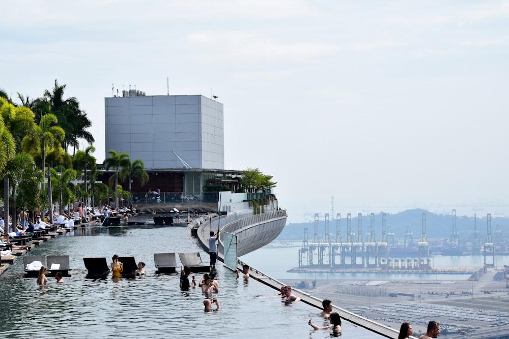 people in swimming pool viewing buildings and mountain under white and blue sky during daytime