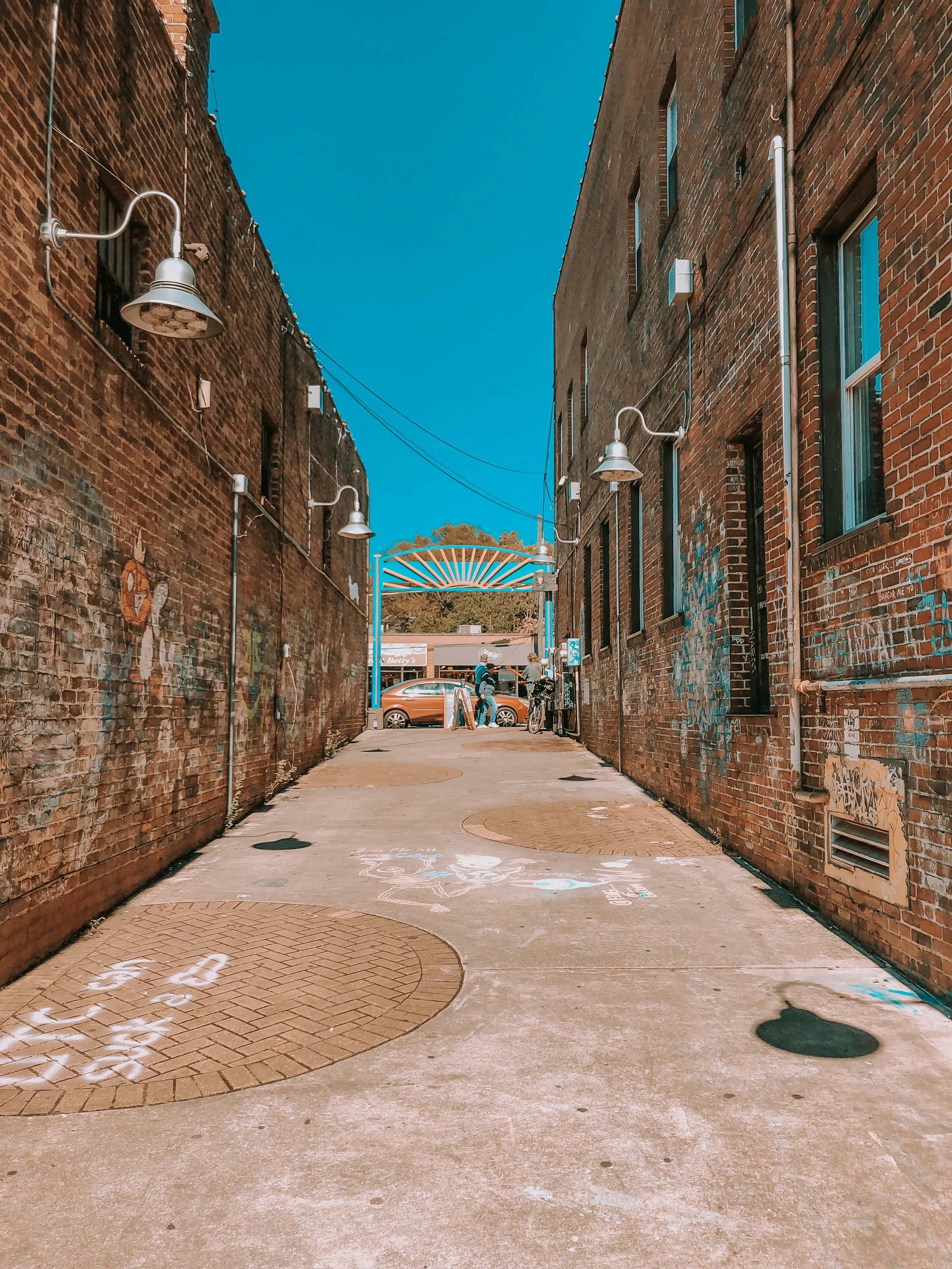 few people near orange vehicle beside brown buildings during daytime