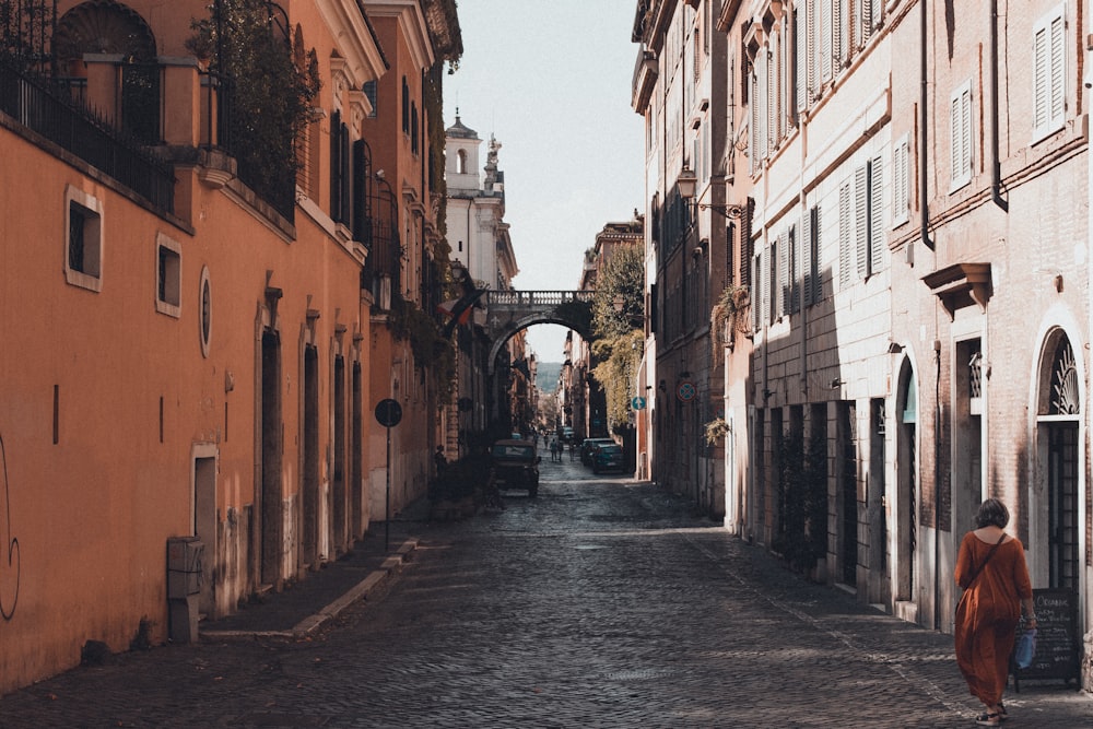 woman walking near road beside buildings during daytime