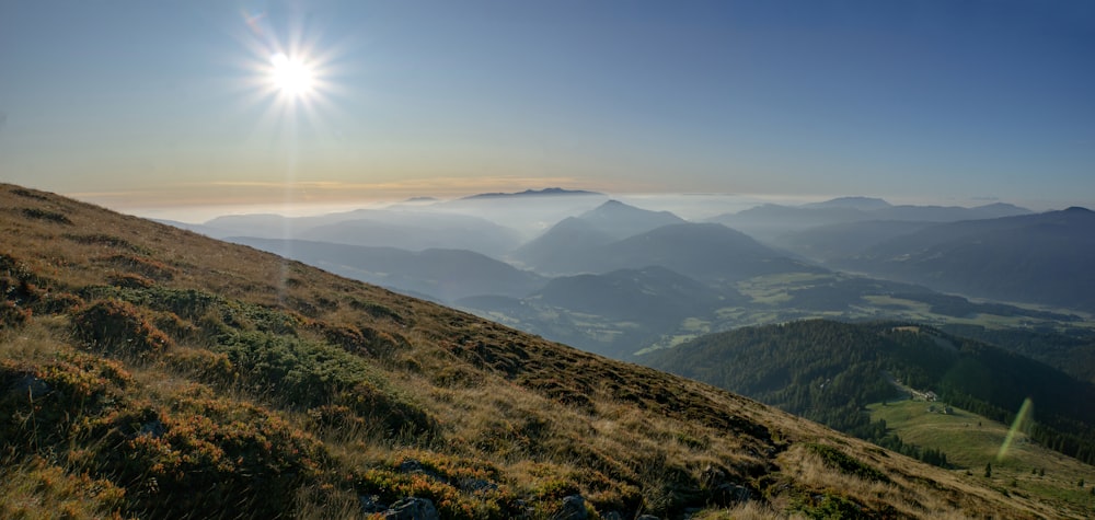 aerial photography of green field viewing mountain under blue and yellow sky during daytime