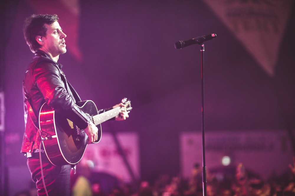 man playing guitar standing on stage