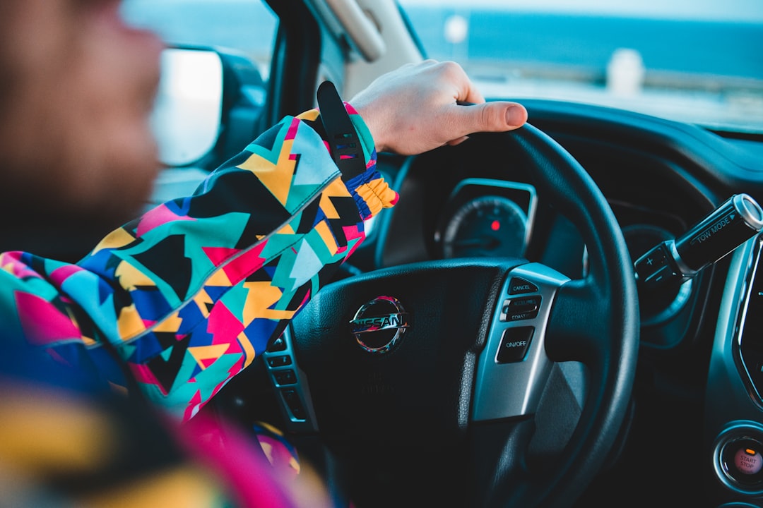 selective focus photography of person driving Nissan vehicle