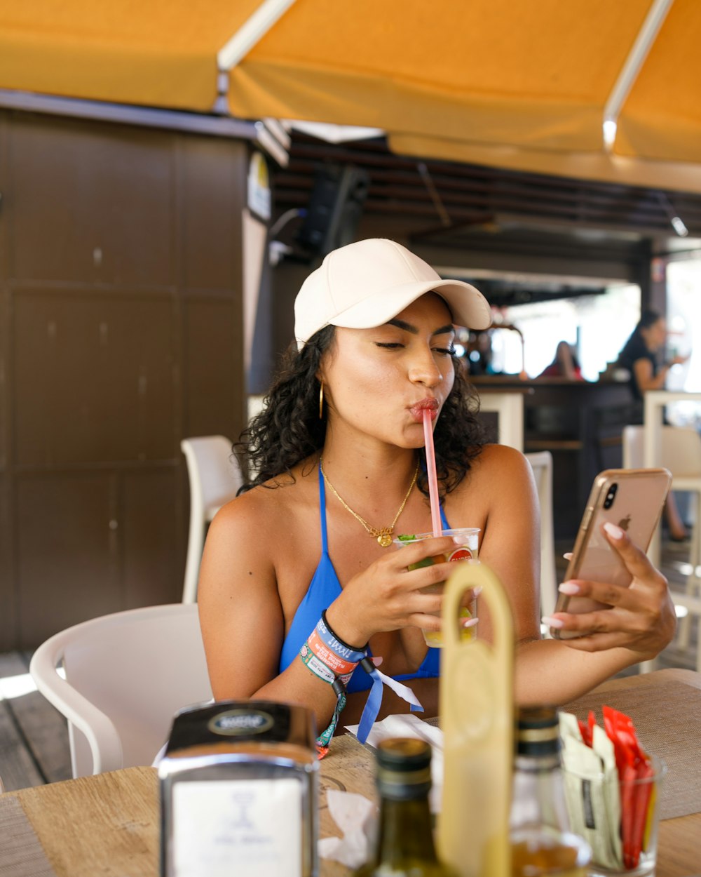 woman in blue bikini top sopping from straw