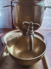 Close-up of a handcrafted brass chafing dish with soft ivory and gold accents, highlighting intricate artisan details.