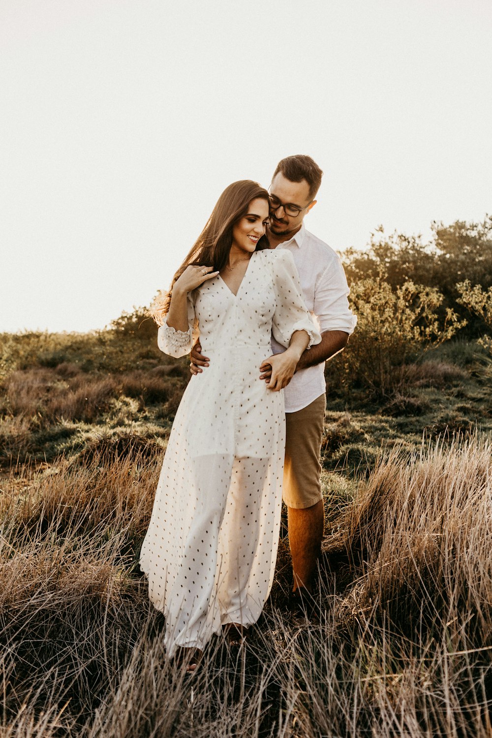 flaches Foto eines Mannes, der eine Frau in einem weißen langärmeligen Kleid umarmt