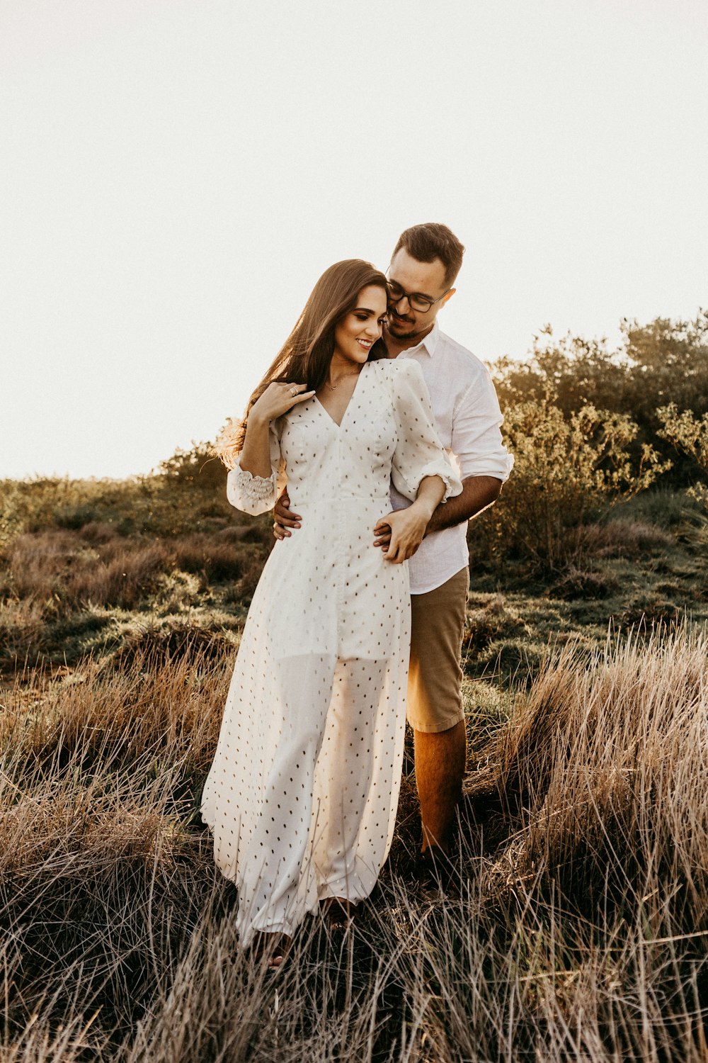 shallow focus photo of man hugging woman in white long-sleeved dress