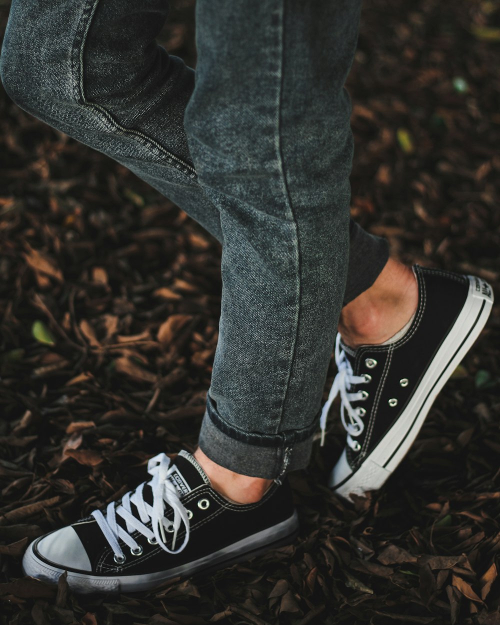 standing person wearing gray denim jeans and low-top sneakers