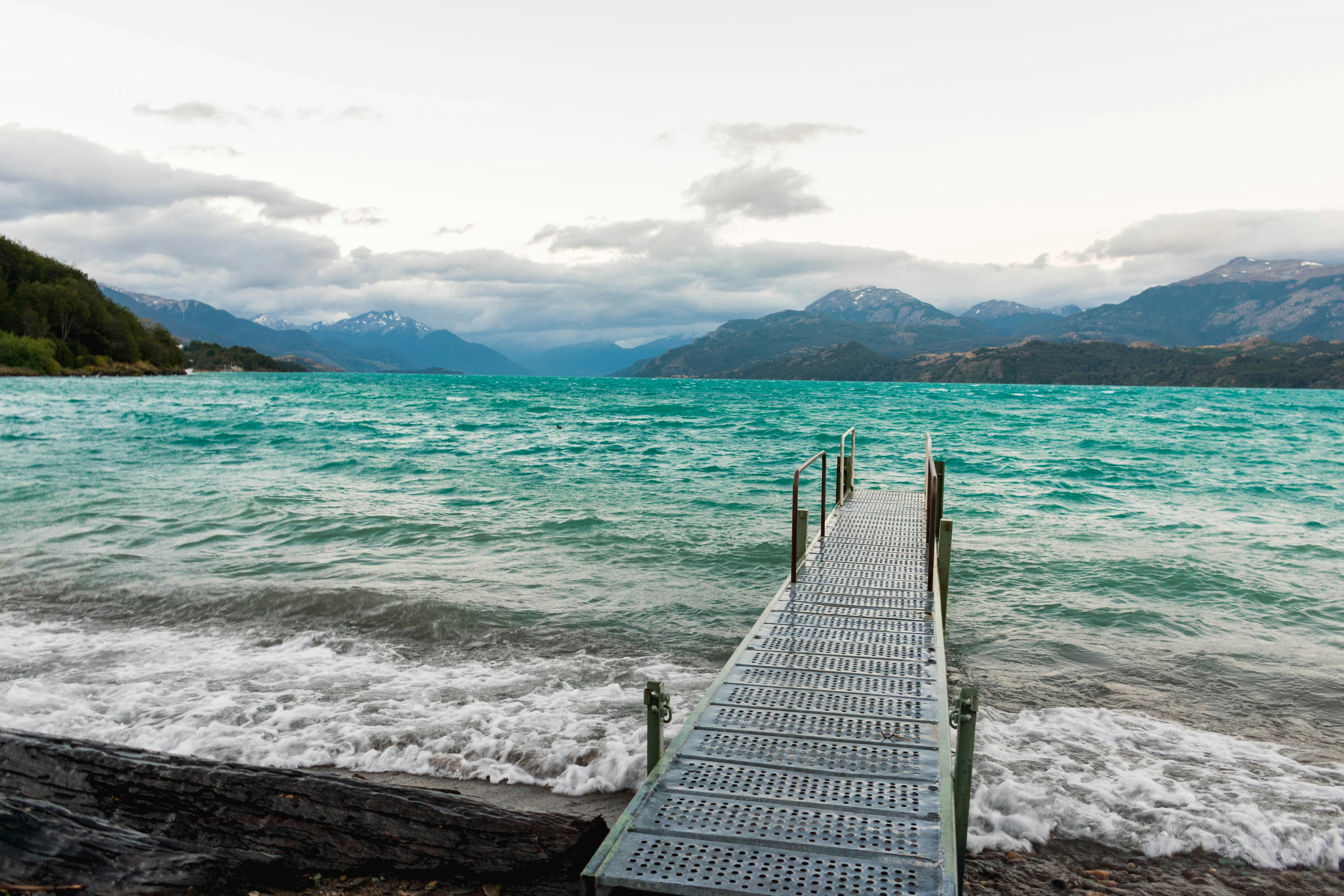 aerial photography of gray dock viewing body of water and mountain during daytime