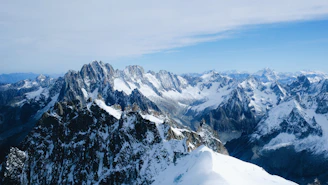 A panoramic view capturing the vastness of an ice mountain range under a clear blue sky.