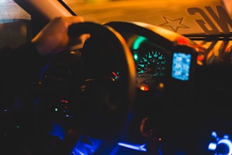 Nighttime photo of a luxury car's illuminated dashboard and steering wheel.