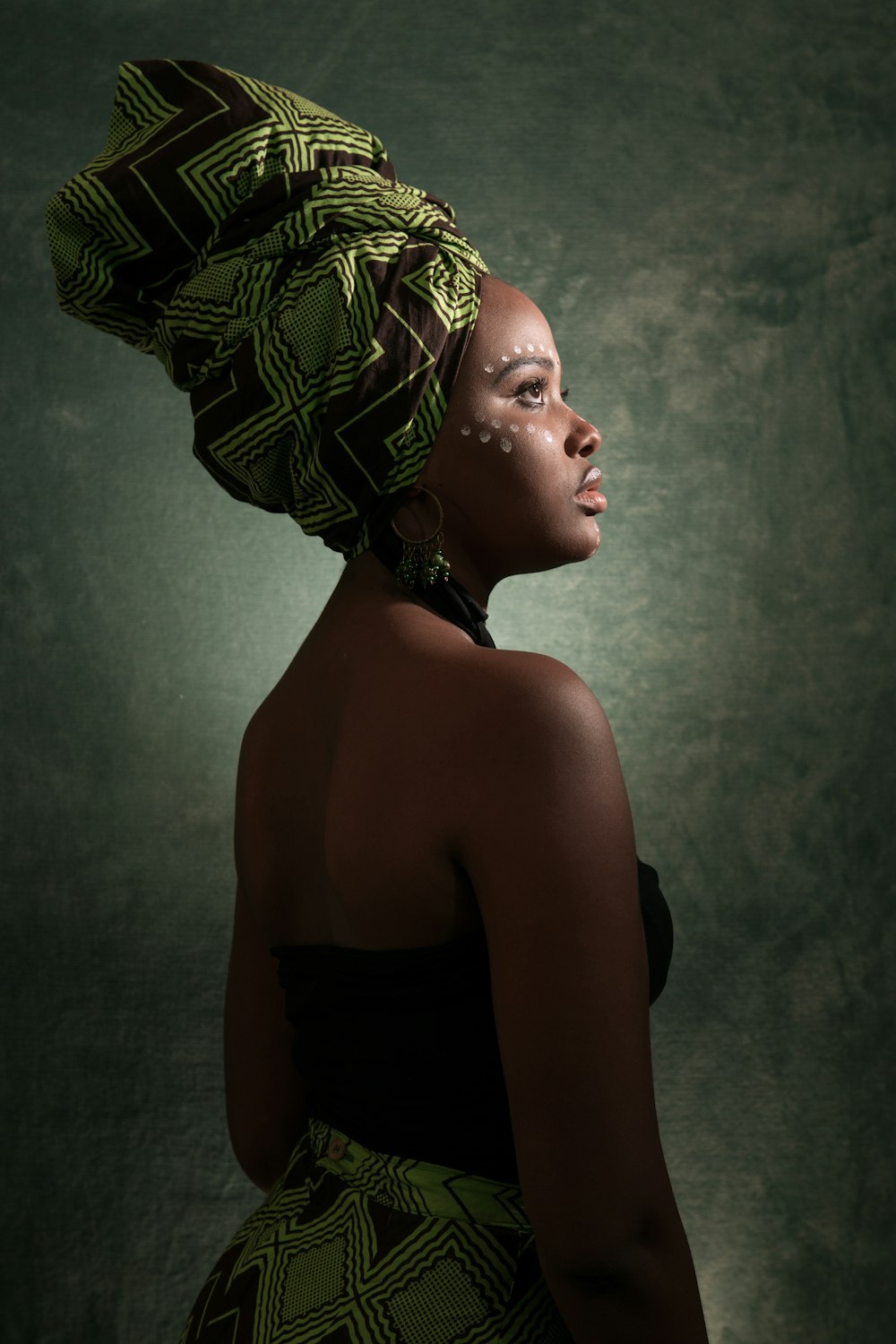 woman in black and green tube-top dress with turban