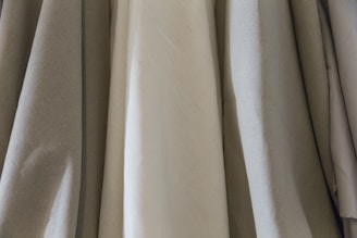 Close-up of soft, natural fabrics draped elegantly on a wooden display.