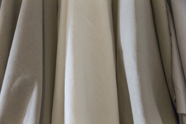 Close-up of soft, natural fabrics draped elegantly on a wooden display.