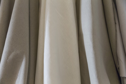 Soft, flowing fabric samples draped over a wooden table, showcasing texture and color.