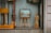A shop window display contains a variety of handcrafted wooden items, including an easel with a framed picture, a standing wooden figure, and some other wooden objects. The word 'handicraft' is visible on a sign in the bottom left corner. The display conveys an artistic and artisanal vibe, with reflections on the glass slightly blurring the view.