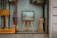 A shop window display contains a variety of handcrafted wooden items, including an easel with a framed picture, a standing wooden figure, and some other wooden objects. The word 'handicraft' is visible on a sign in the bottom left corner. The display conveys an artistic and artisanal vibe, with reflections on the glass slightly blurring the view.