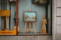 A shop window display contains a variety of handcrafted wooden items, including an easel with a framed picture, a standing wooden figure, and some other wooden objects. The word 'handicraft' is visible on a sign in the bottom left corner. The display conveys an artistic and artisanal vibe, with reflections on the glass slightly blurring the view.