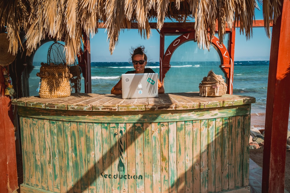 woman sitting on tiki bar facing silver laptop