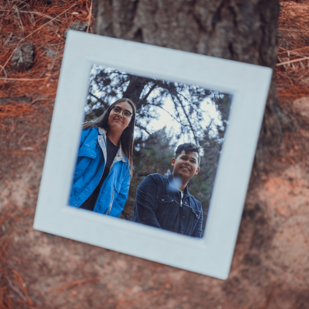 photo of woman and man wearing jackets with white wooden frames