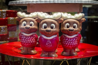 A cozy scene showing a group of plush reindeer with different expressions sitting together on a wooden shelf.